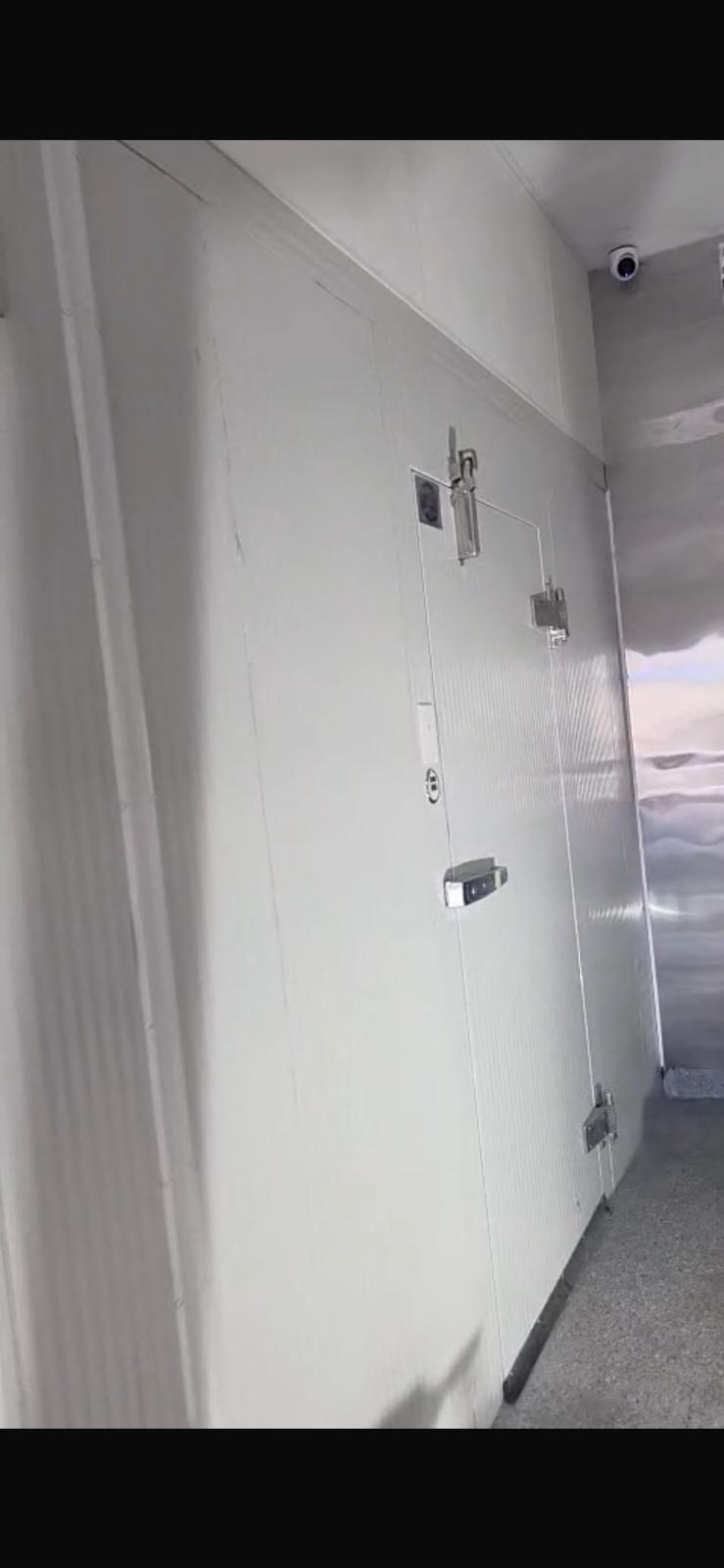 A corridor of installed Foster USA walk-in cooler panels with stainless interior and overhead monitoring